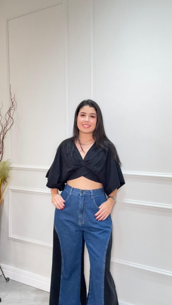 Blusa preta e soltinha estilo cropped com detalhes transpassados. Mangas largas.