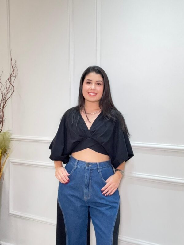 Blusa preta e soltinha estilo cropped com detalhes transpassados. Mangas largas.