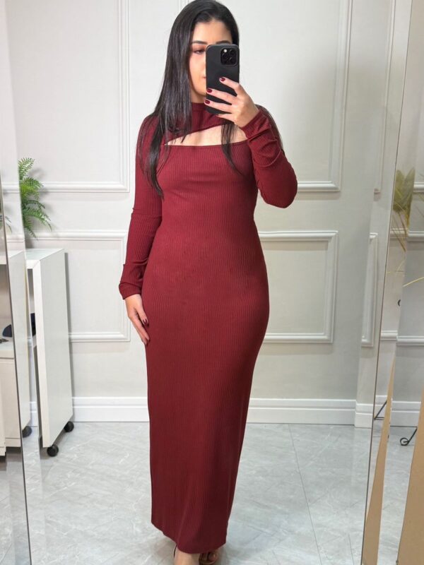 Vestido longo canelado forma justa cor marsala com mangas longas, gola alta, e decote assimétrico.